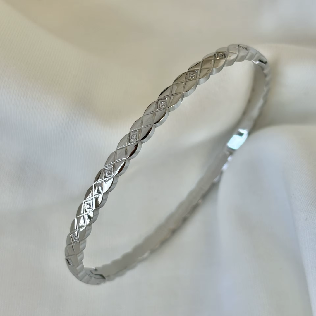 18K silver plated non tarnish bangle with glass crystal stones on a white fabric background.