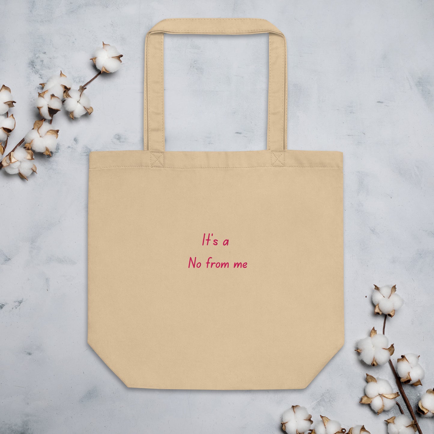 Beige It's a No from Me organic cotton Slogan embroidered eco tote bag on a blank white surface with some cotton plants at the sides.