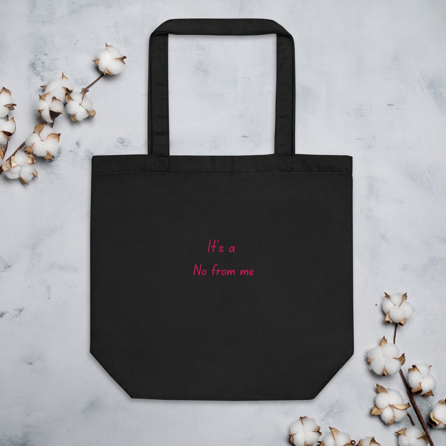 Black It's a No from Me organic cotton Slogan embroidered eco tote bag on a blank surface with cotton plants at the sides.