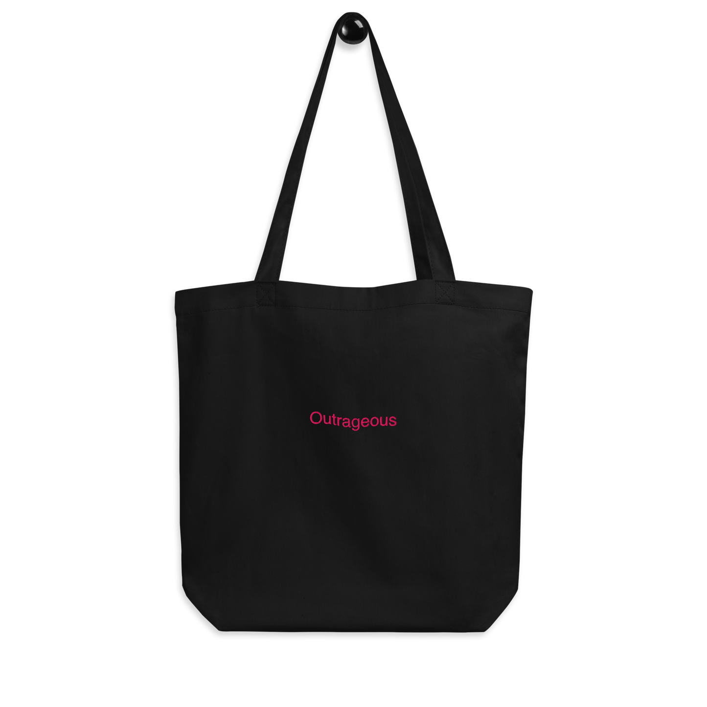 Black outrageous Slogan embroidered eco tote bag on a blank surface hanging on a hook.