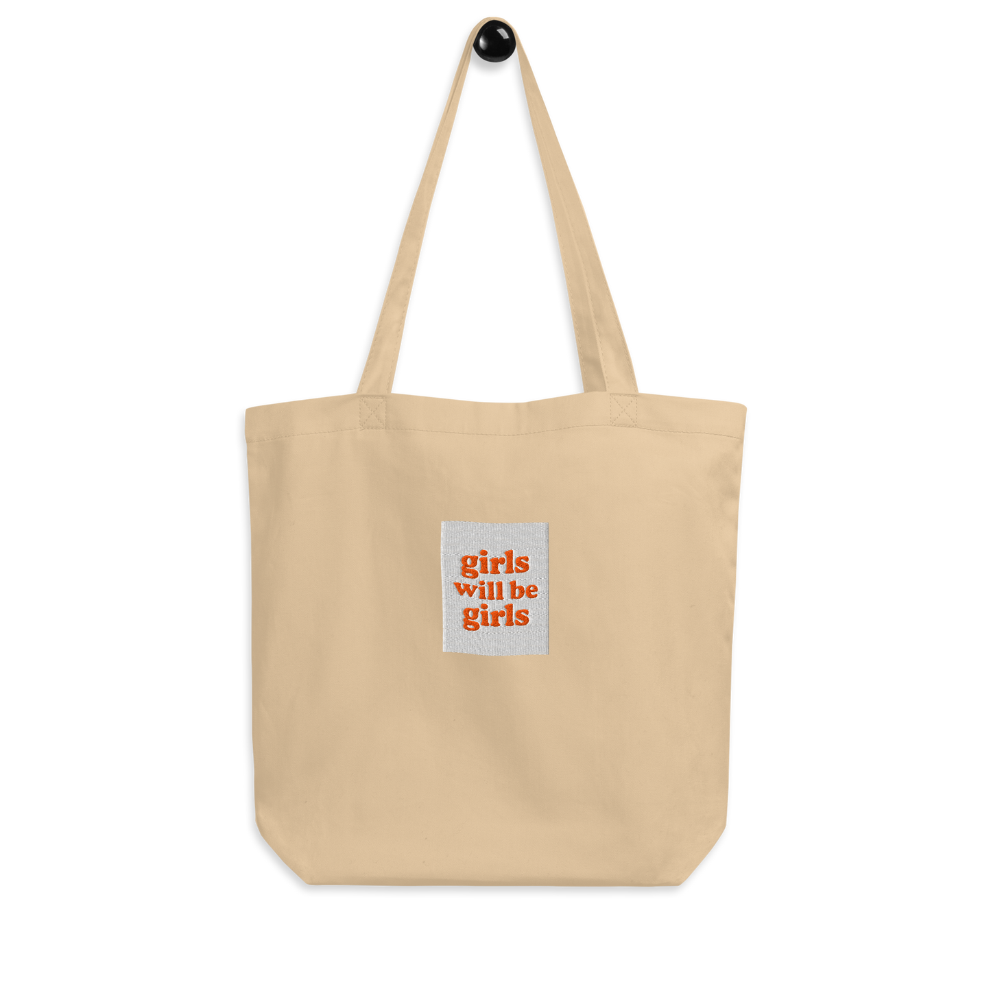 Oyster tote bag with a small embroidered square patch with the words girls will be girls on a white background.