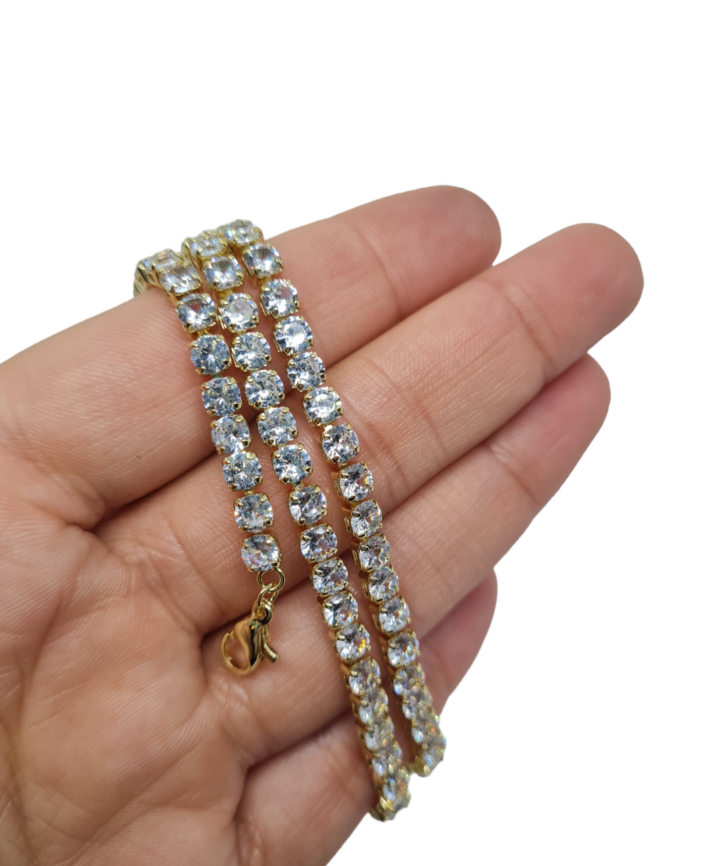 A gold plated stoned sparkle necklace wrapped around a hand on a white background.