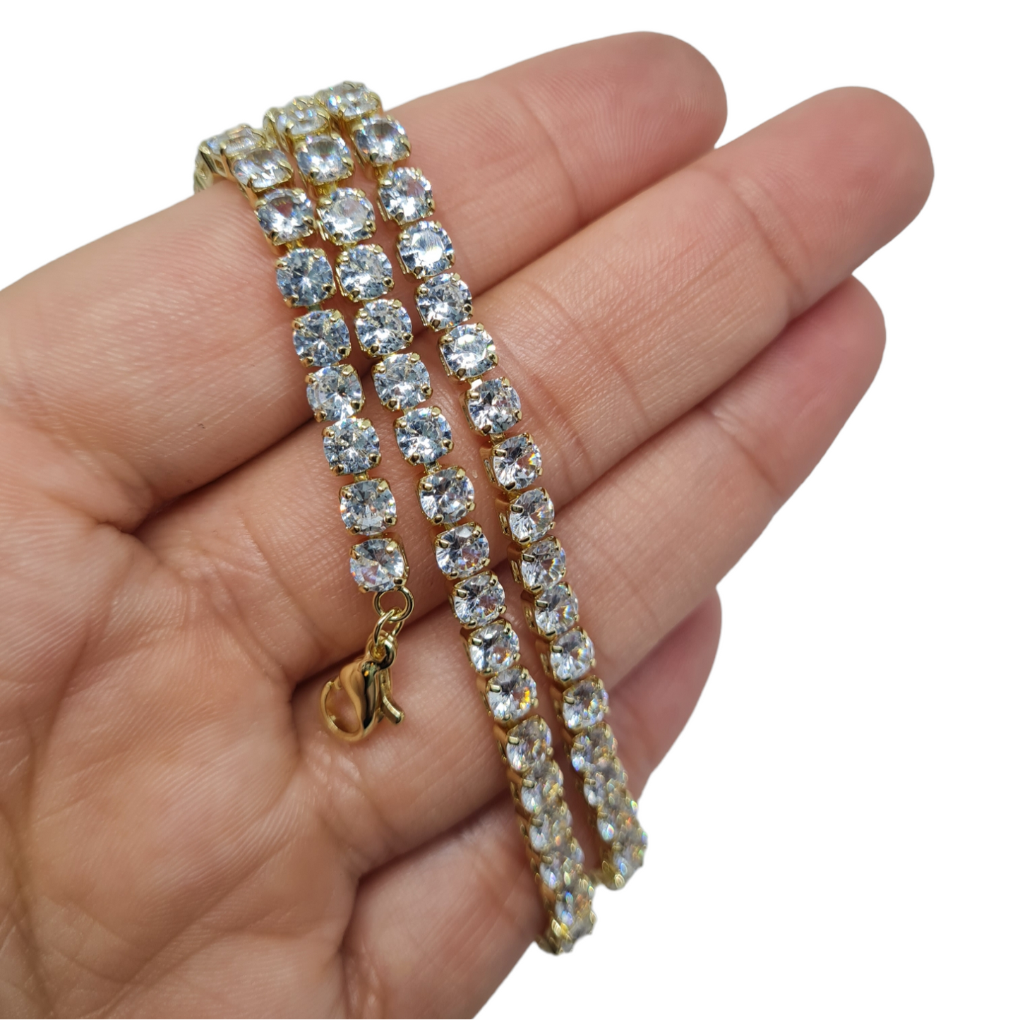 A gold plated stoned sparkle necklace wrapped around a hand on a white background.