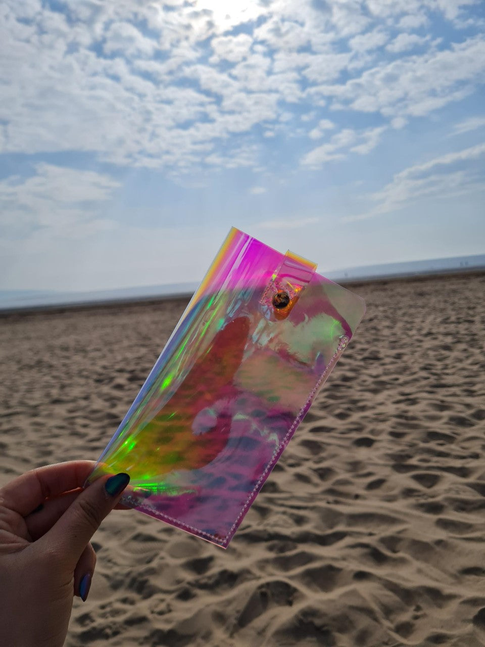 Neon Sunglasses Case being held up at the beach with a view of the ocean.