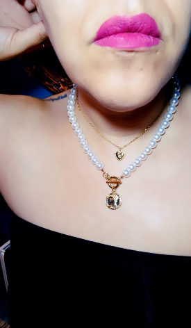 A gold-plated necklace with white pearls and a coin-shaped pendant, displayed on a pretty girl in a boob tube.