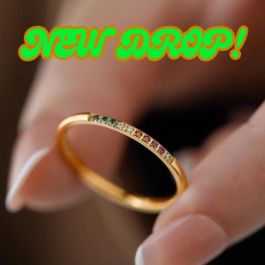 Pretty 18K Gold Plated Stainless Steel Rainbow Band Ring with embedded gemstones held between fingers.