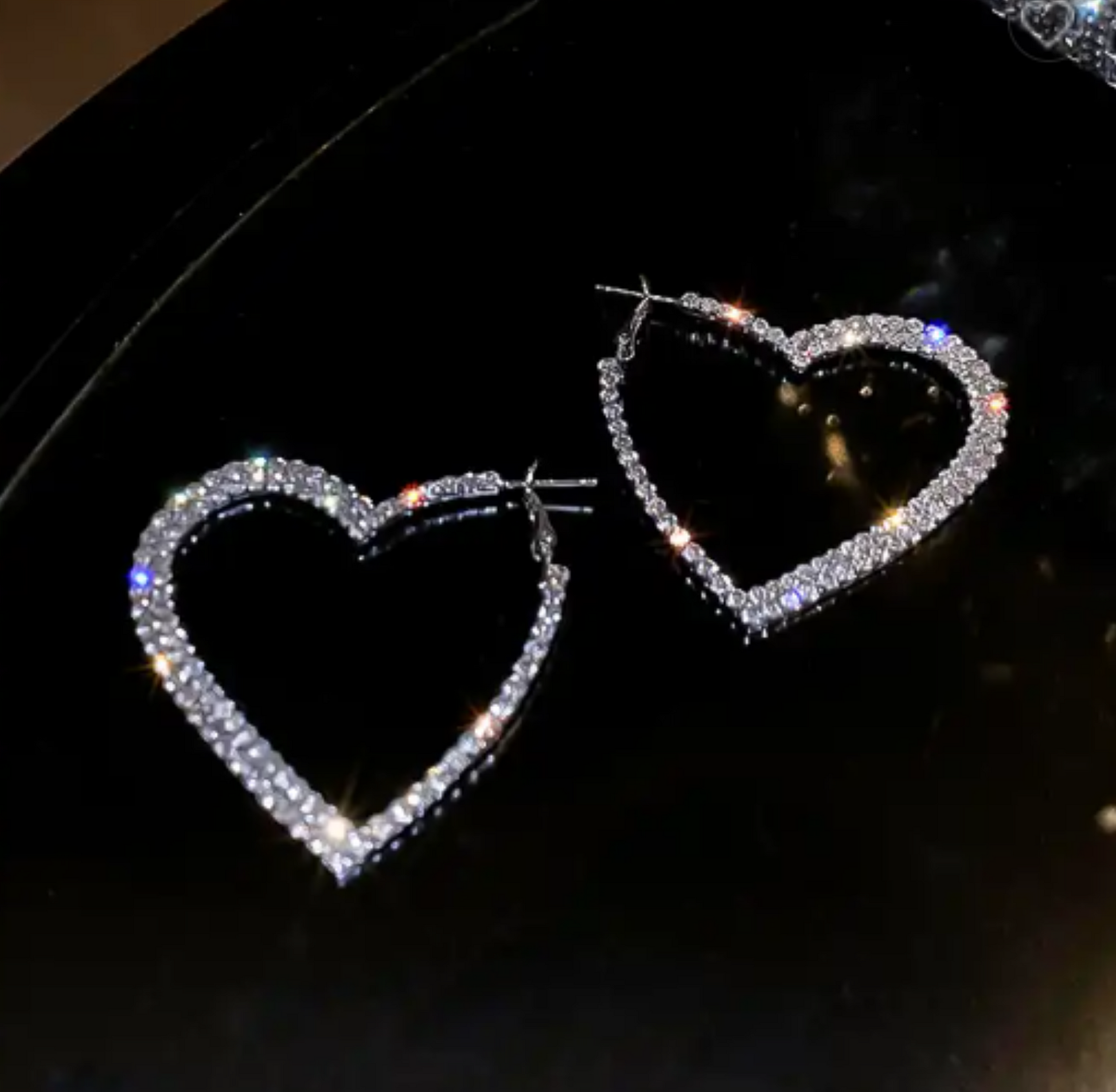 A pair of 925 Silver Plated sparkle heart hoops on a black background.