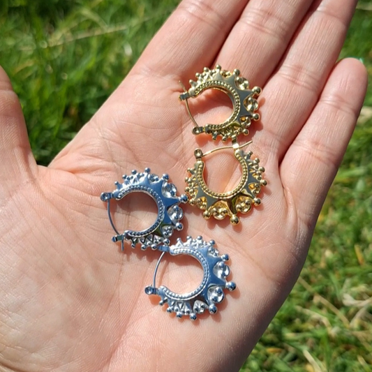 A hand laid flat folding 2 pairs of Arabian creole hoops in the sun.