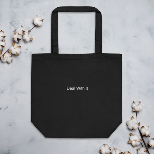 Black Deal with It Slogan embroidered eco tote bag on a blank surface with cotton plants on the side.