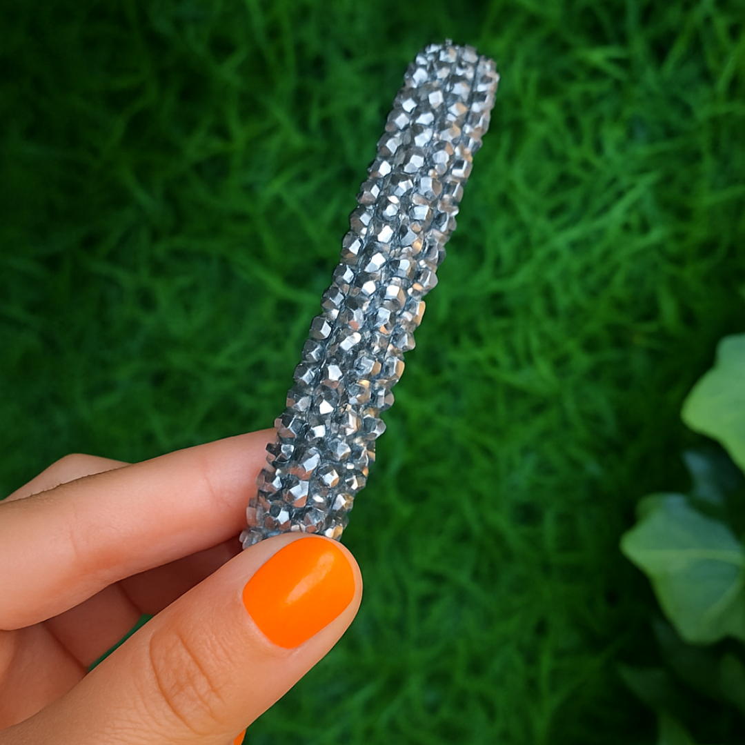 A Charcoal sparkle beaded headband being held up by a hand with orange nail varnish.