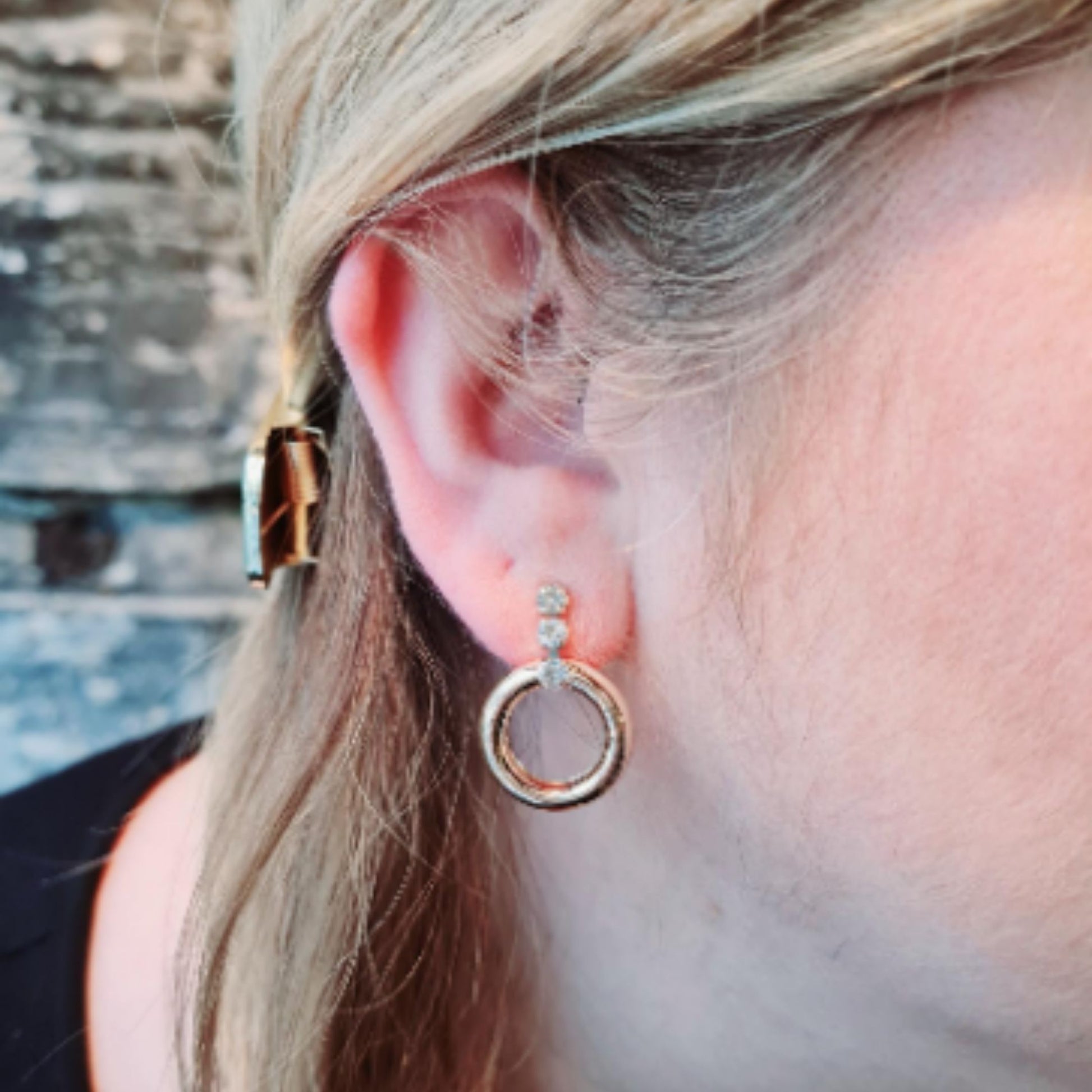Gold Plated Crystal Sparkle Drop Earrings on an earlobe with a blurred background.