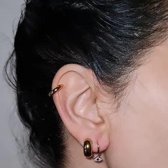 Evil eye drop hoop earrings with a blue crystal in the eyes on a girl with some ear cuffs.