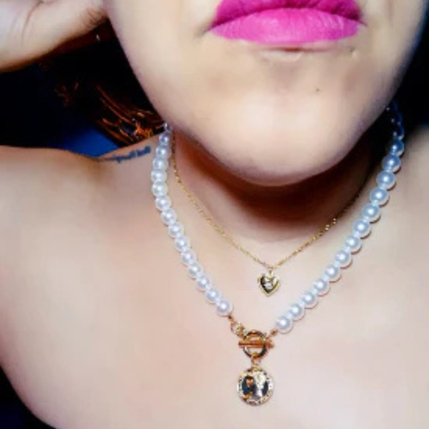 Pearl necklace with a heart pendant worn by a person with pink lipstick.