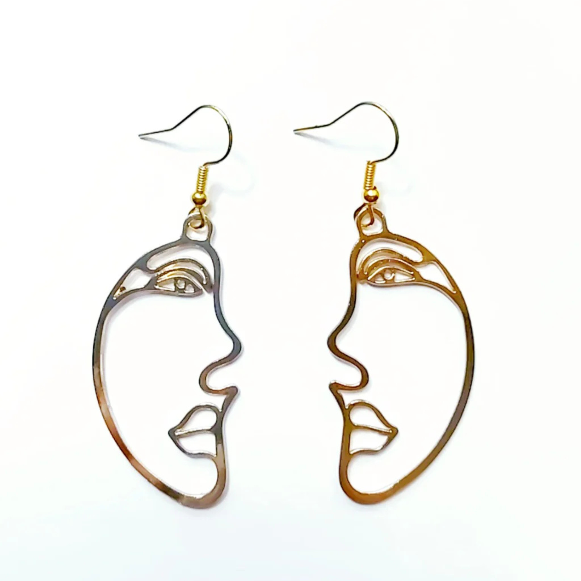 Pair of face-shaped earrings in gold on a white background