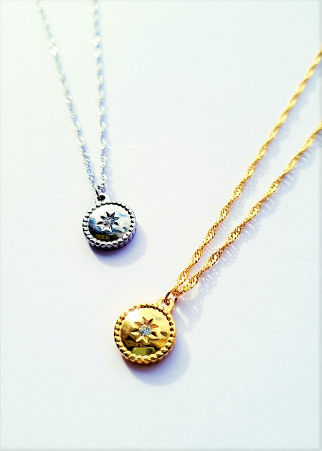 Two silver-plated stainless steel circle necklaces with one featuring a star pendant and the other a round crystal pendant.