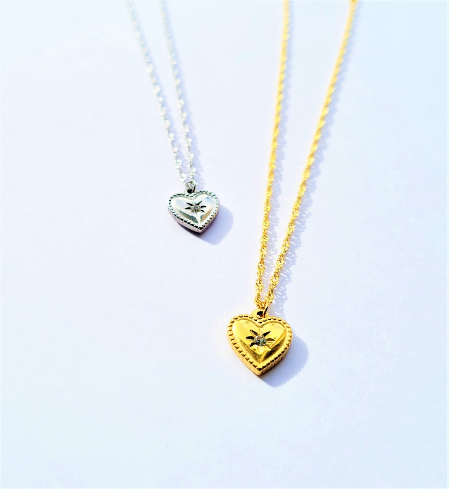 2 Gold and Silver plated stainless steel heart-shaped necklaces on a white background.