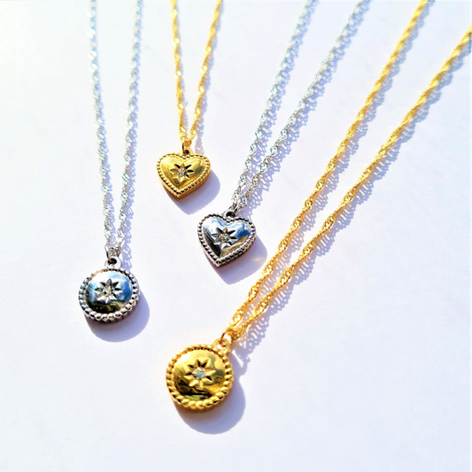Four heart-shaped pendants on gold and silver chains against a white background