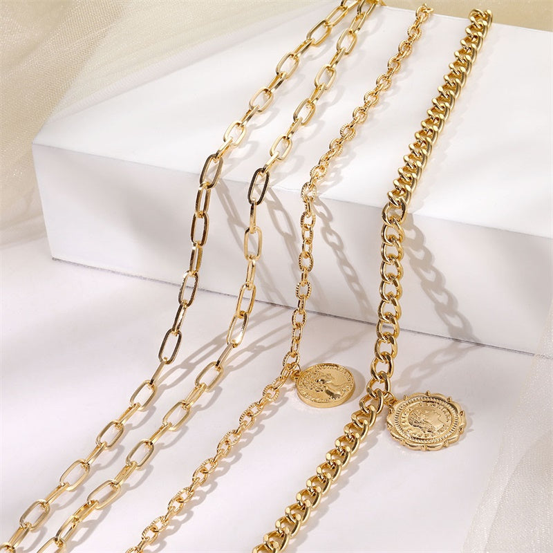 A gold-plated ,multi layer chunky coin necklace displayed on a white surface.