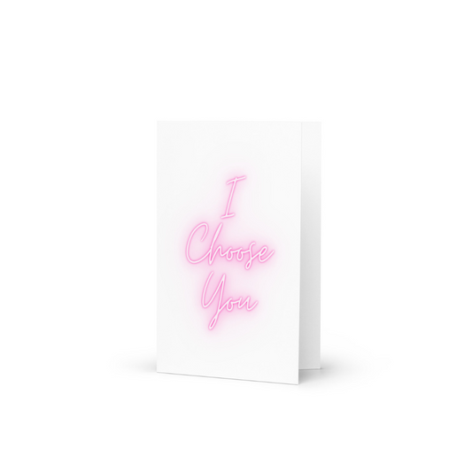 A white greeting card with the phrase I Choose You in a neon pink glow font.
