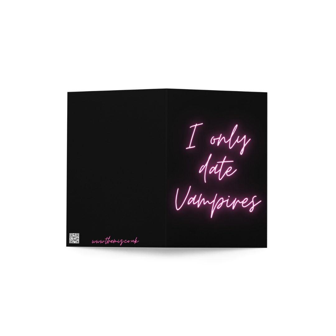 Greeting card with pink neon text saying 'I only date Vampires' on a black background.