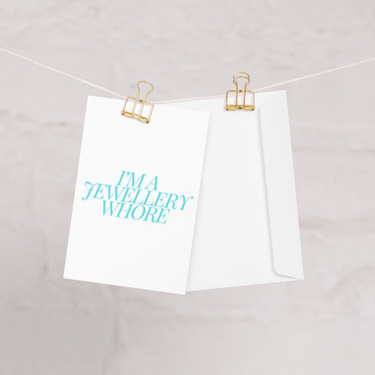 Jewellery Whore Greeting Card hanging on a washing line with two gold clips.
