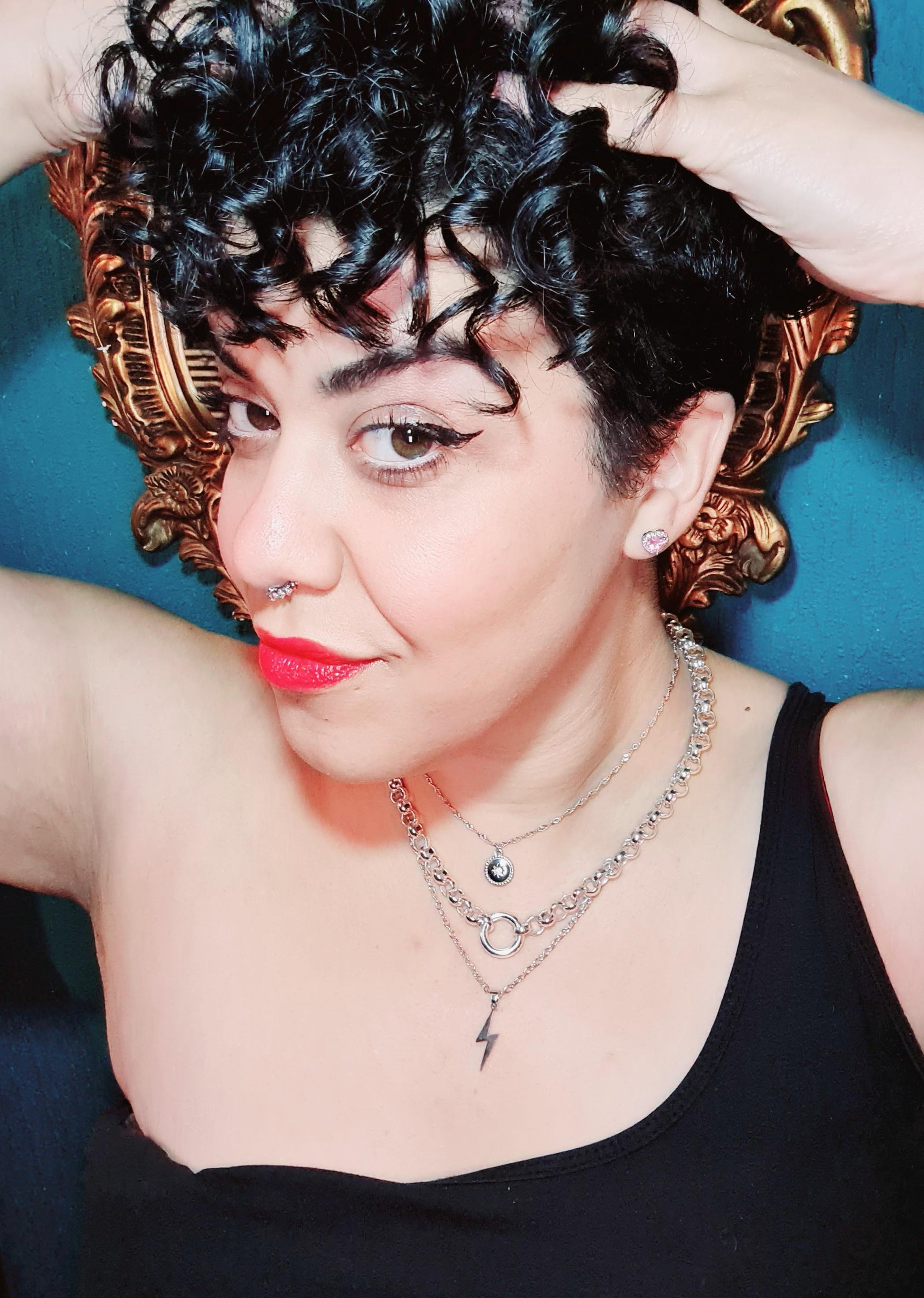 A pretty girl wearing 3 layered necklaces and a sparkle nose ring.