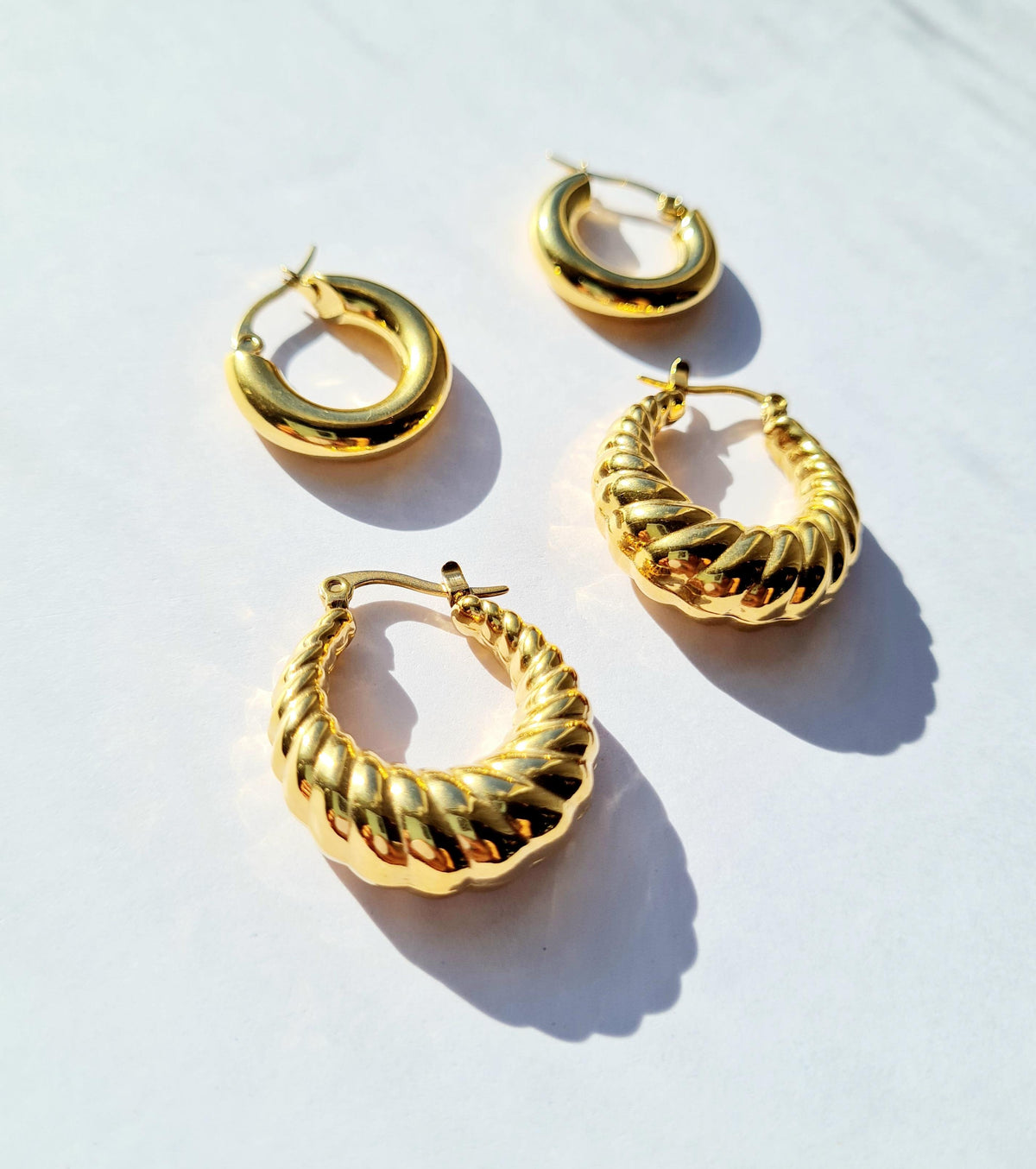 A pair of scallop hooped earrings and Smooth Mini Hoops with 18K gold plating, displayed on a light background.