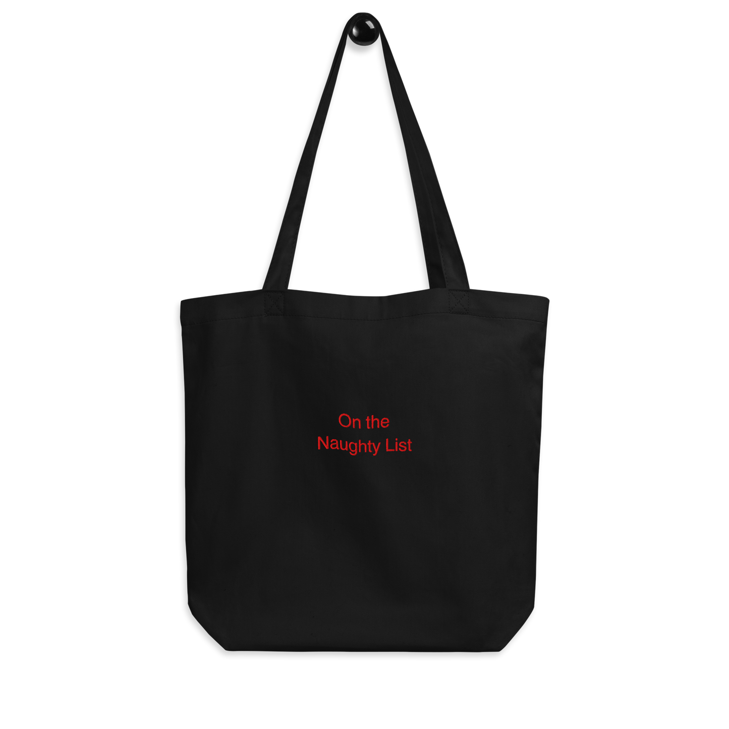Organic Cotton Tote Bag in black with a slogan at the front that says on the naughty list embroidered in red thread on a white background.