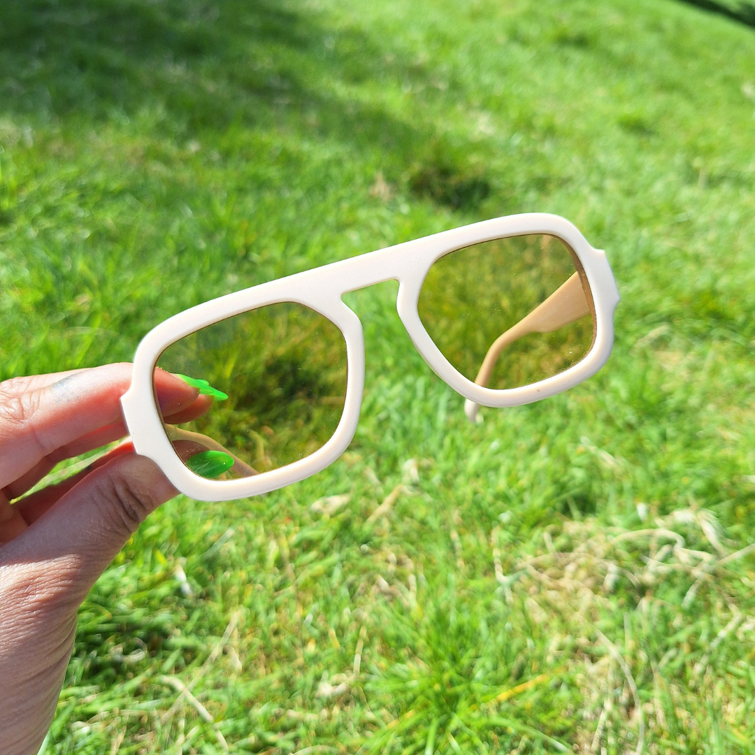 Nude Retro Sunnies being held up in the park in the sun.