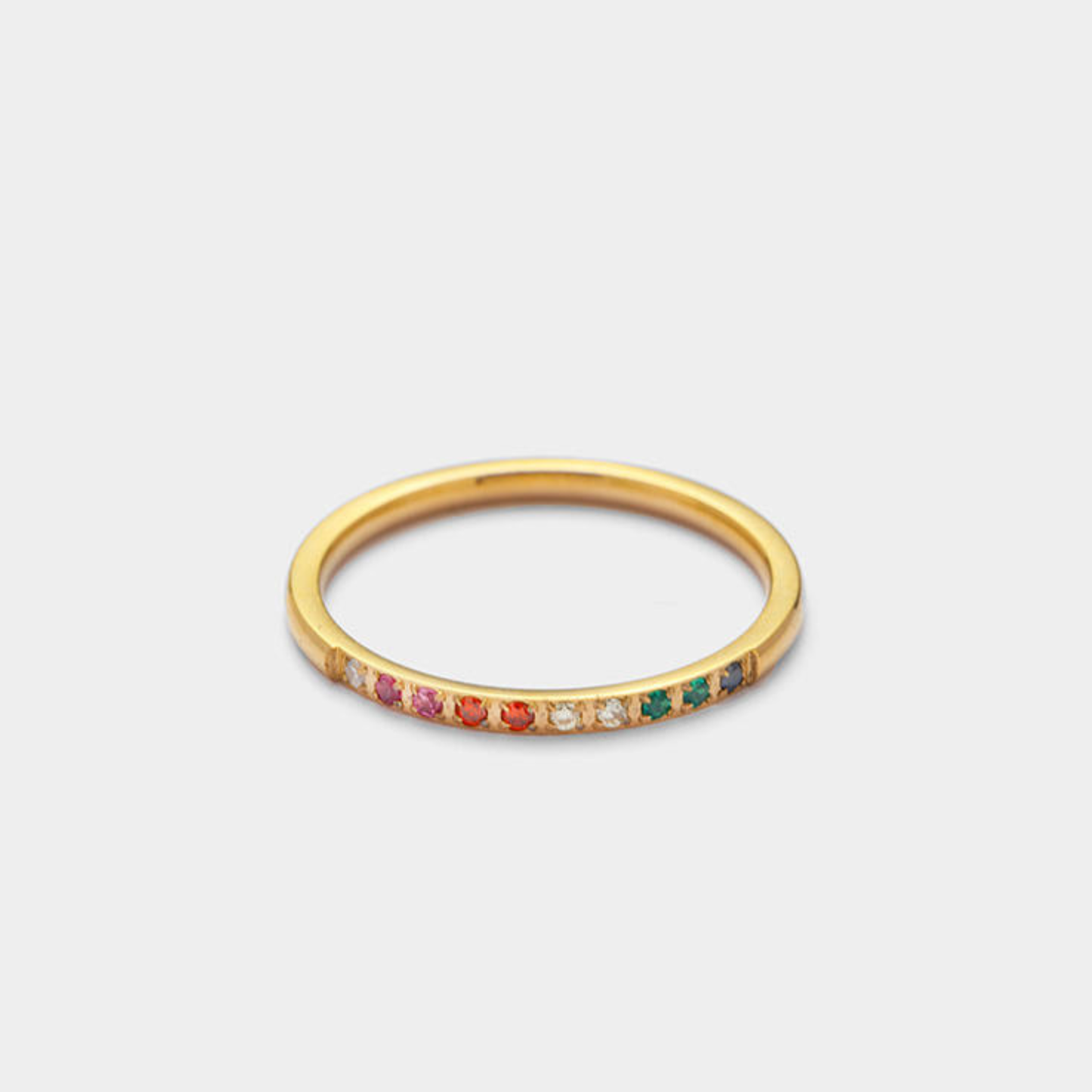 Pretty 18K Gold Plated Stainless Steel Rainbow Band Ring with colourful gemstones on a light grey. background