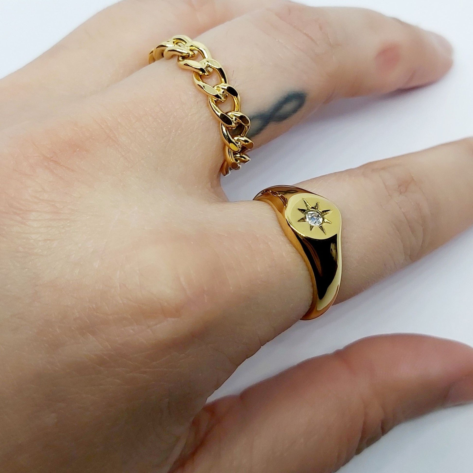 Rockstar Gold Plated Curb Chain Ring and a gold plated signer ring on a hand with a white background.