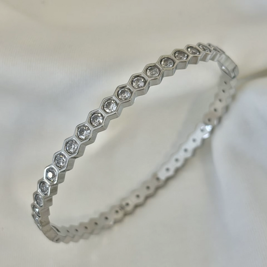 18K Gold plated bangle with glass crystal stones on a soft white fabric background.