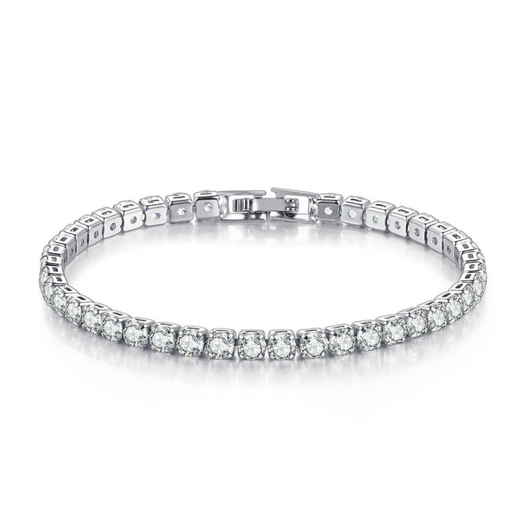 A silver-plated tennis bracelet with sparkling stones, laid out on a plain surface.
