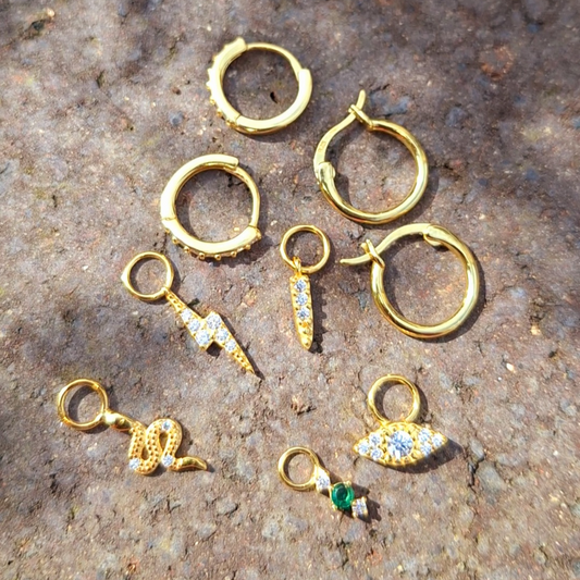 Stainless Steel mini gold hoops with interchangeable charm on a rock flat surface.