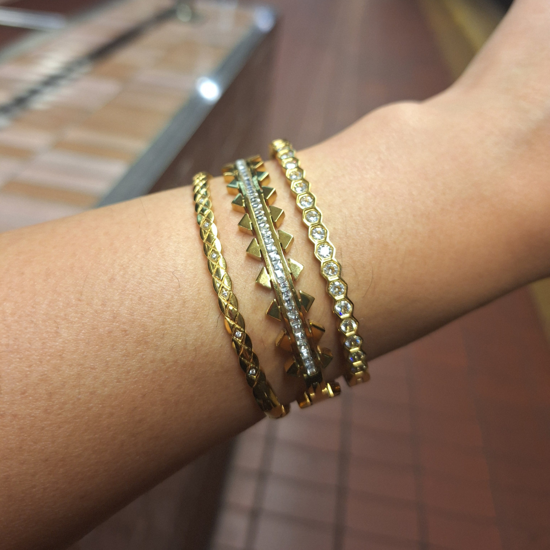 Close-up of a wrist wearing 18K gold plated tarnish free bangles on a blurred background. 