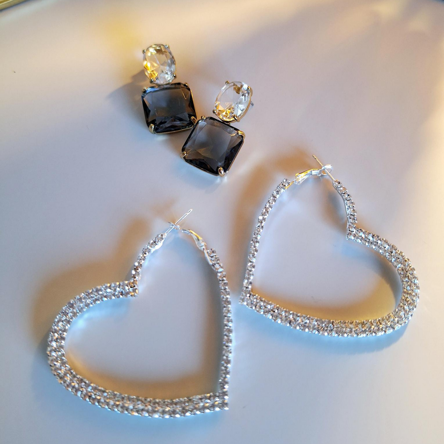 A pair of upcycled gold plated blue lux drop earrings and sparkle heart hoops on a white background.