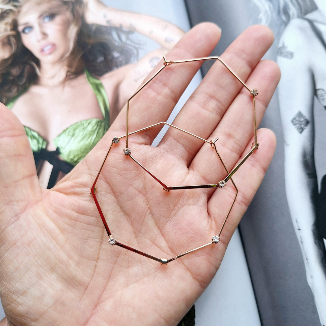 Upcycled octagonal gold plated hoops held in a hand.