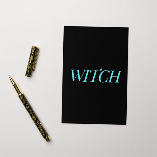 A funny witch greeting card on a white surface with a vintage fountain pen at the side.