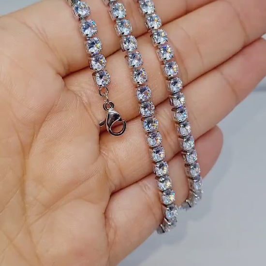 A silver plated stoned sparkle necklace wrapped around a hand on a white background.