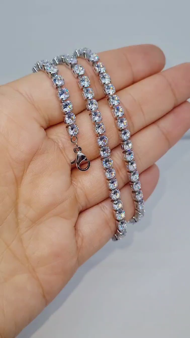 A silver plated stoned sparkle necklace wrapped around a hand on a white background.