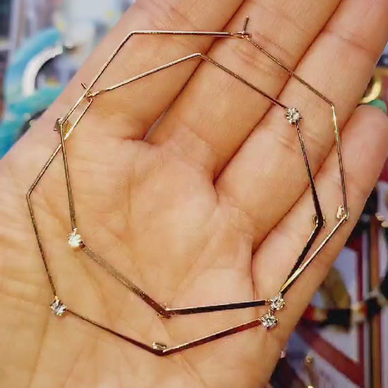 Upcycled octagonal gold plated hoops held in a hand video.