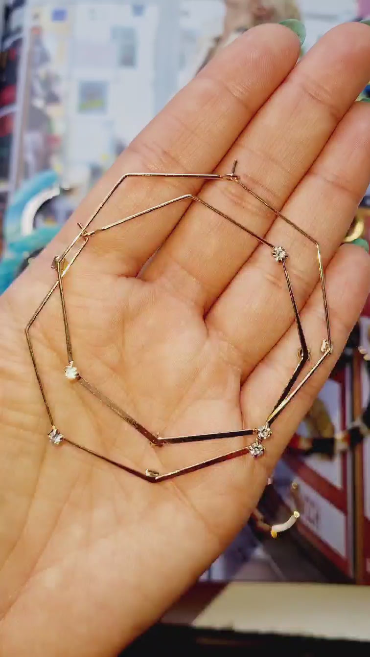 Upcycled octagonal gold plated hoops held in a hand video.
