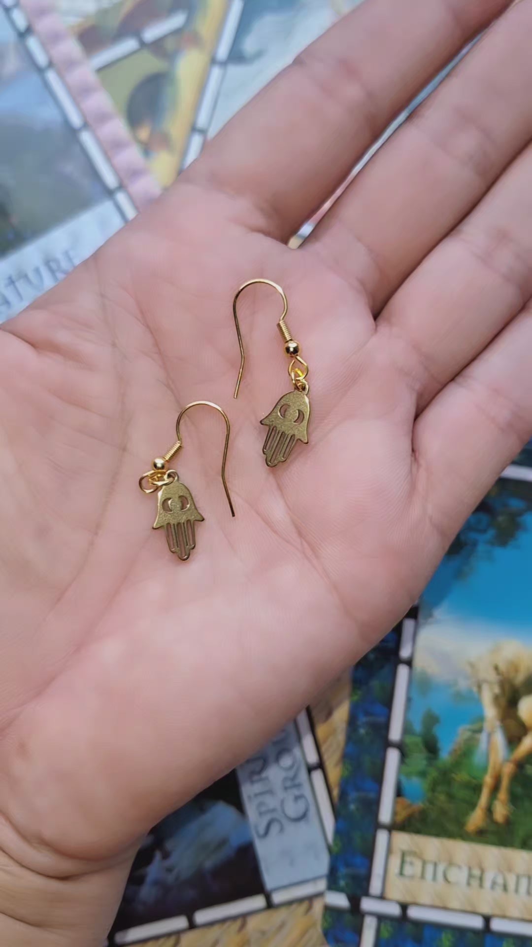 Gold Plated Fatima Hand Earrings featuring the shape of the Fatima hand symbol, displayed on a wooden surface.